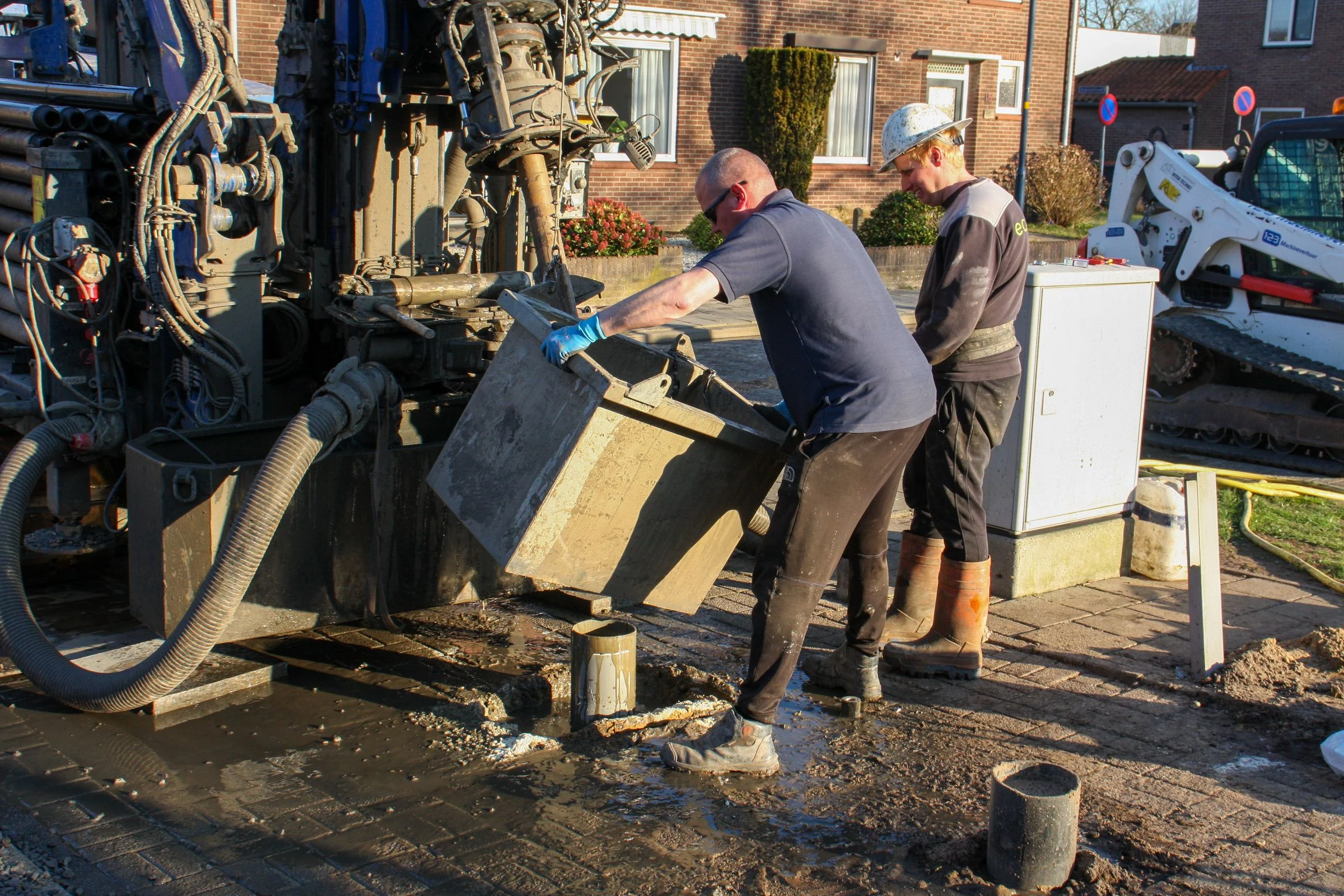 Workers coordinating drilling equipment on an outdoor site